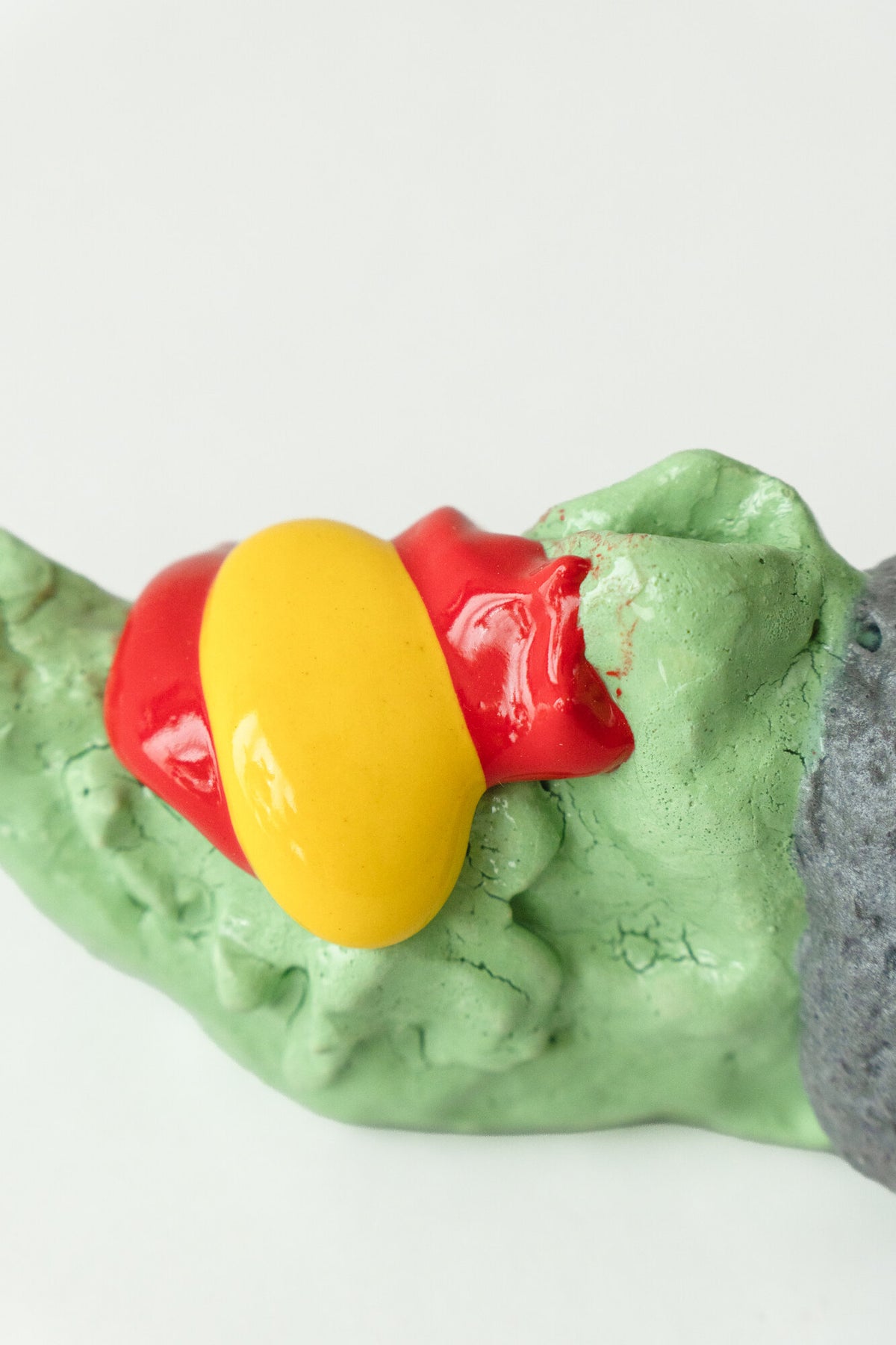Foam #9 by Onree: Low green ceramic form with a dark textured section and glossy red and yellow additions — additional view 2