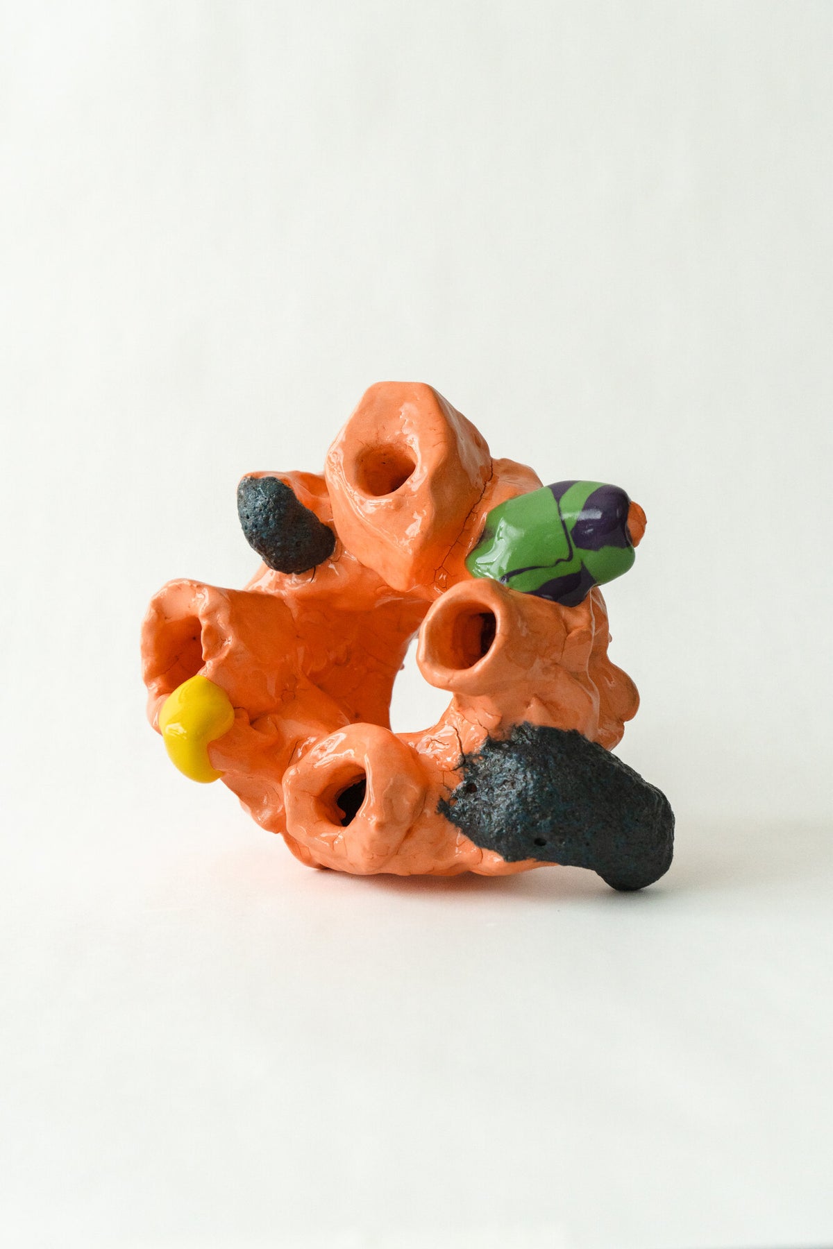Foam #1 by Onree: Orange looping ceramic form with several openings, bright glazed accents and dark textured projections — full view