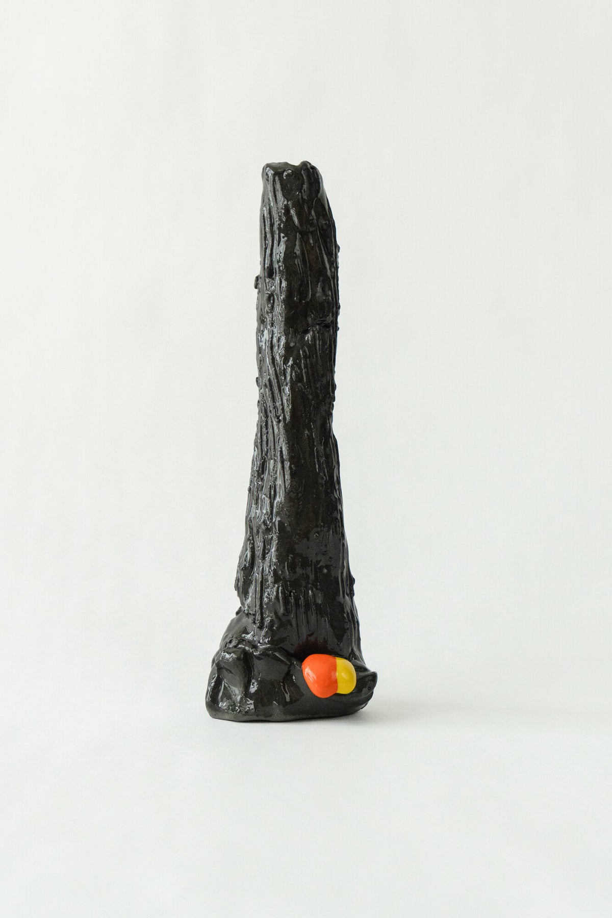Foam #6 by Onree: Slender black ceramic form with an uneven surface and orange and yellow accents at its base — full view