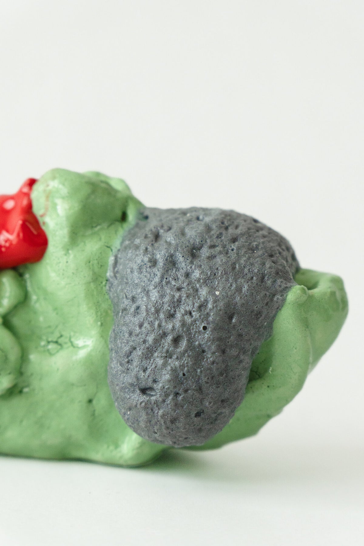 Foam #9 by Onree: Low green ceramic form with a dark textured section and glossy red and yellow additions — additional view 1