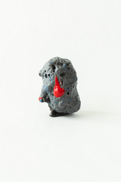 Foam #17 by Onree: Dark grey upright ceramic form with a pitted surface and red glazed accents — full view