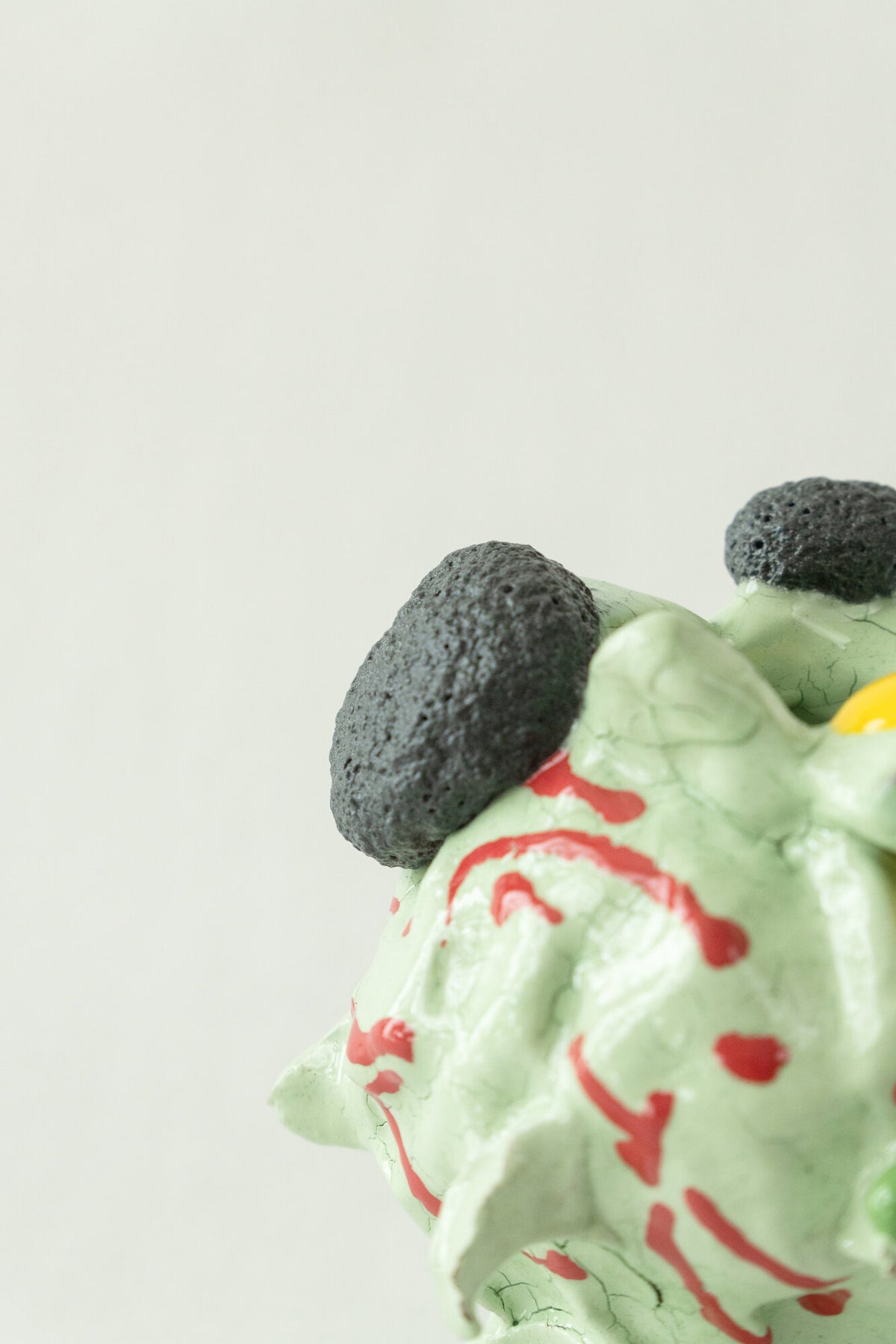 Foam #23 by Onree: Pale green ceramic vessel with red marks, dark textured circles and a yellow glazed detail — additional view 1