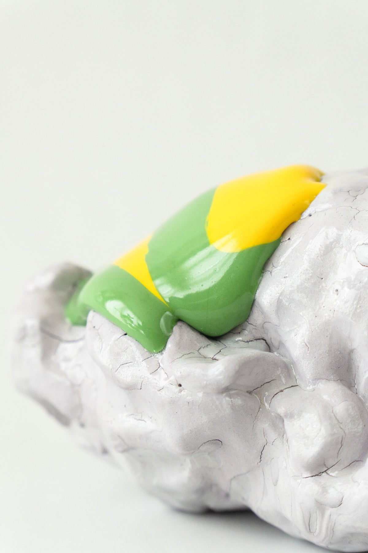 Foam #29 by Onree: Low white ceramic form with green, yellow and orange glaze and a dark textured detail — additional view 2
